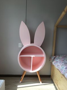 a pink shelf with ears on it next to a bed