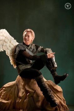 a man dressed as an angel sitting on top of a rock holding a water bottle