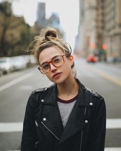 a woman wearing glasses standing in the middle of a street