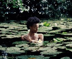 a woman sitting in the water surrounded by lily pads