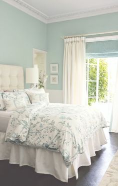 a white bed sitting in a bedroom next to a window with curtains on both sides