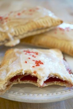 two pastries on a plate with white icing and red sprinkles