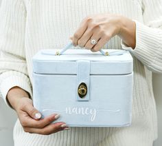 a woman holding a blue box with the word fancy written on it in white lettering