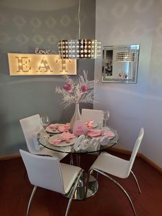 a glass table with white chairs around it and a sign that says eat on the wall