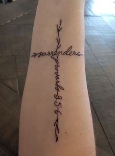 a cross tattoo on the arm with words written in cursive writing