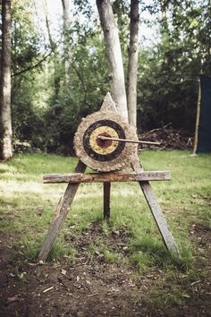 an archery target in the middle of a wooded area with trees and grass behind it