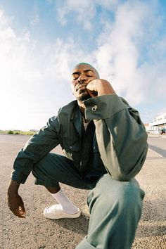 a man sitting on the ground talking on a cell phone while holding his hand up to his ear