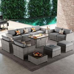 an outdoor living room with grey wicker furniture and a pool in the back ground