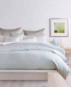 a bed with blue and white comforters in a bedroom next to a wooden table