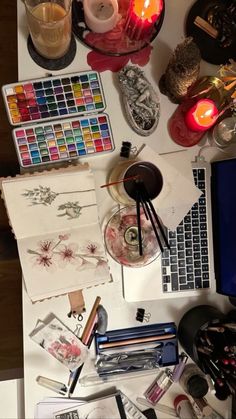 the desk is cluttered with art supplies, candles, and other things on it