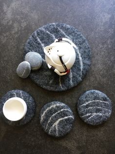 a tea pot and some rocks on a black counter top with a white cup in the middle