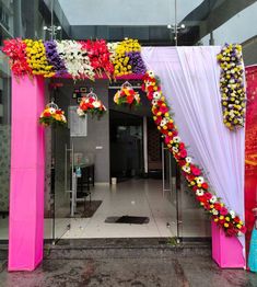 an entrance to a building decorated with flowers and white draping on the outside