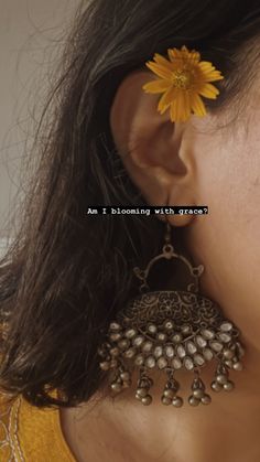 a close up of a person wearing earrings with a flower in the middle of their ear