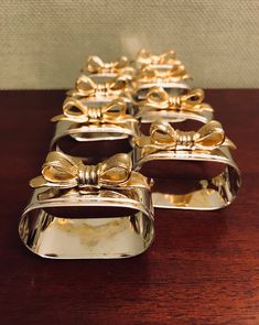 four gold bow shaped dishes sitting on top of a wooden table