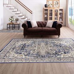 a living room filled with furniture and a rug on top of a hard wood floor