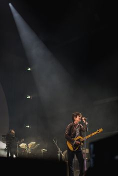 a man standing on top of a stage holding a guitar