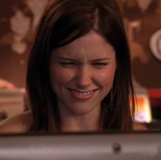 a woman smiling while looking at her computer screen