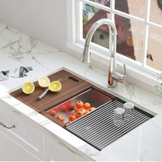 a kitchen sink with a cutting board in the middle and lemons on the counter