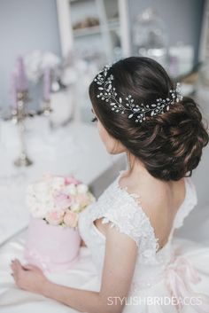 a woman in a wedding dress is holding a cake with flowers on it and wearing a tiara