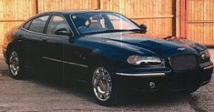 a black car parked in front of a wooden fence