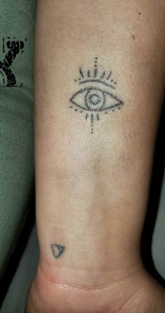 a woman's arm with an evil eye tattoo on it