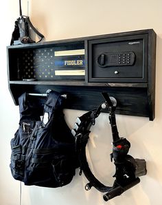 a black wall mounted shelf with a camera and some bags on it next to a tripod