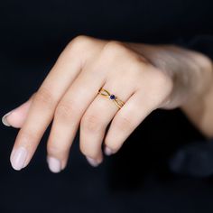 a woman's hand with a yellow gold ring and blue sapphire stones on it