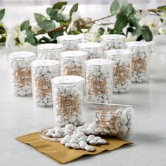 several jars filled with white and brown candies sitting on top of a table next to flowers