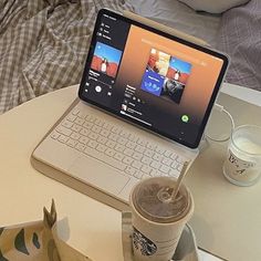 an open laptop computer sitting on top of a table next to a cup of coffee