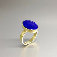 Oval classic Lapis Lazuli ring with 18k gold. Unique gift for her, girlfriend, wife, September and December birthstone, anniversary gift. This ring is a timeless classic and lets the stone speak with all its natural beauty. This beautiful ring is worked with the technique of inlay, which means the stone is worked seamlessly into the 18K gold.All our stones are natural stones and our jewelry is handmade, slight differences in color and size may occur. Our inlay work is made with real stone and NO Elegant Gold Rings With Tanzanite, Elegant Gold Tanzanite Rings, Timeless Blue Oval Cabochon Jewelry, Timeless Tanzanite Rings As Gift, Timeless Tanzanite Rings For Gifts, Yellow Gold Tanzanite Rings, Yellow Gold Tanzanite Ring With Polished Finish, Timeless Oval Cabochon Sapphire Ring Gift, Classic Tanzanite Rings With Bezel Setting