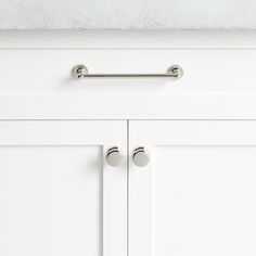 a white cabinet door with two handles and knobs