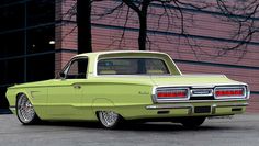 an old green car parked in front of a building