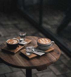 two cups of coffee sitting on top of a wooden table