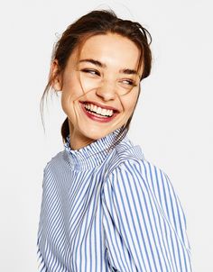 a smiling woman wearing a blue and white striped shirt