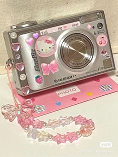 a hello kitty camera sitting on top of a table next to a bracelet and necklace