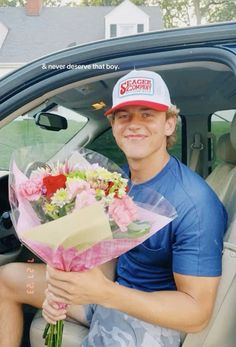 a man sitting in the back seat of a car holding flowers and a paper bouquet