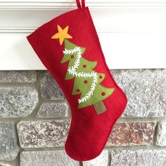 a red christmas stocking hanging on a brick wall next to a fire place with a green tree