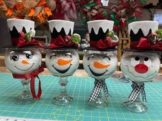 four snowmen are sitting in wine glasses on a table