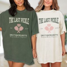 two women standing next to each other wearing matching t - shirts with the last pickle on them