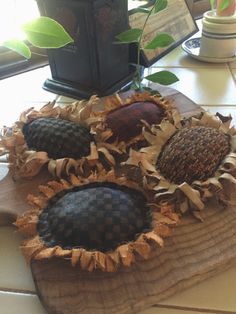 four sunflowers sitting on top of a wooden cutting board next to a potted plant