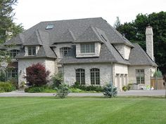 a large brick house sitting on top of a lush green field