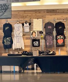 a display in a store with t - shirts hanging on the wall and other items