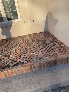 a red brick patio being built in front of a house with a white door and window