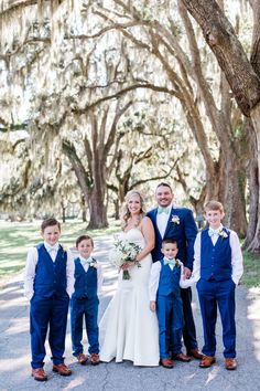 a bride and groom with their children in front of trees