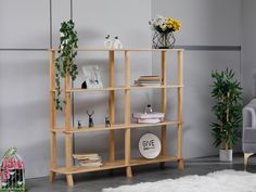 a wooden shelf with books and plants on it in a room next to a gray chair