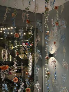 a glass window with flowers hanging from it's sides and lights on the side