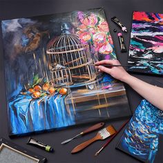 a person is painting flowers in a birdcage with paintbrushes and watercolors