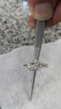 a person holding a diamond ring in front of a pair of scissors