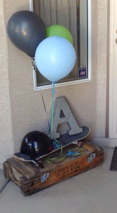 some balloons and a skateboard in front of a door with the letter a on it