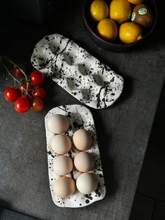 eggs and tomatoes sit on a table next to a bowl of lemons, cherry tomatoes, and an egg carton